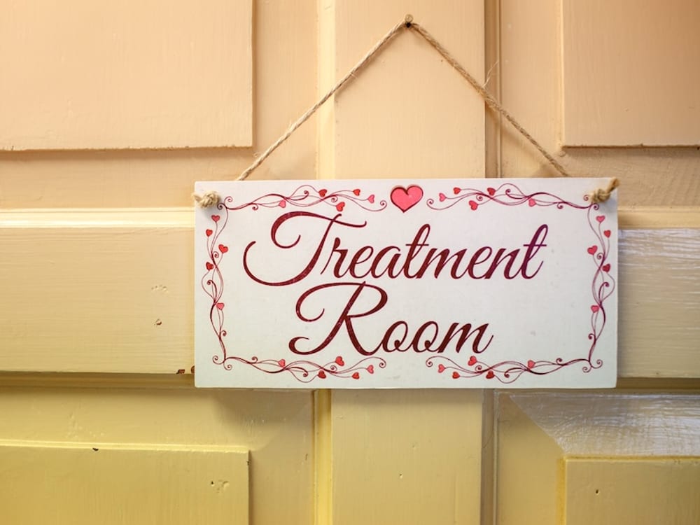 A hand-painted 'Treatment Room' sign hanging on the door of Gemma's therapy room