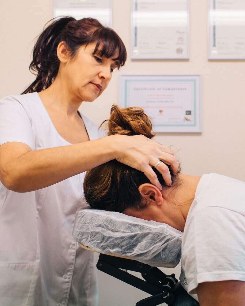 Gemma Avila performing Indian head massage on a client seated at a massage chair